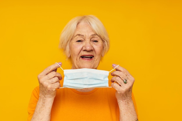 Portret van een oude vriendelijke vrouw gelukkig levensstijl medisch masker gele achtergrond