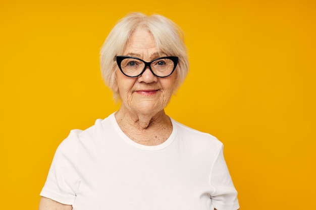 Portret van een oude vriendelijke vrouw in casual t-shirt en glazen close-up emoties