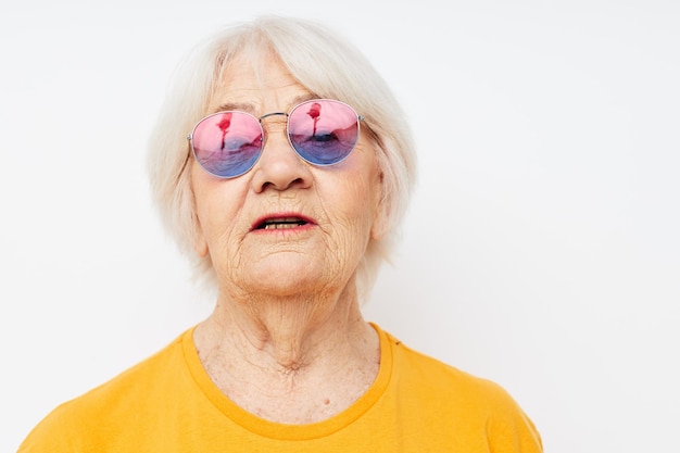 Portret van een oude vriendelijke vrouw in een gele t-shirt poseren geïsoleerde achtergrond