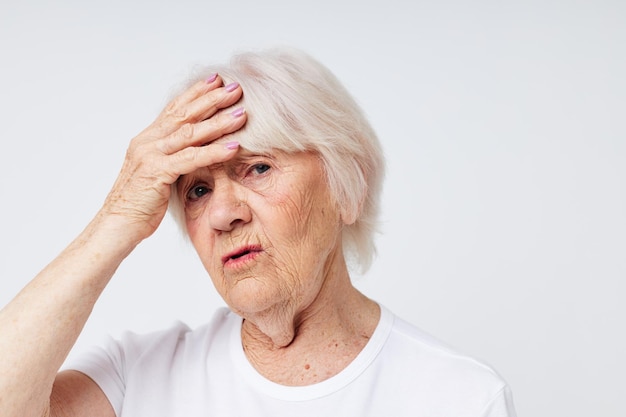 Portret van een oude vriendelijke vrouw met zijn hoofd ontevredenheid probleem lichte achtergrond