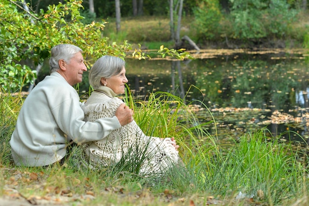 Portret van een ouder echtpaar dat in de herfst in de buurt van het meer zit
