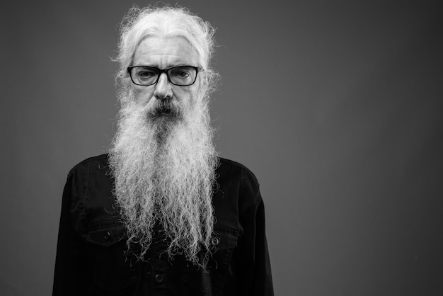 Foto portret van een oudere bebaarde man met een zwart shirt op grijs in zwart-wit