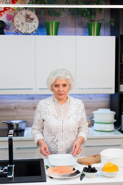 Portret van een oudere blonde vrouw in de keuken