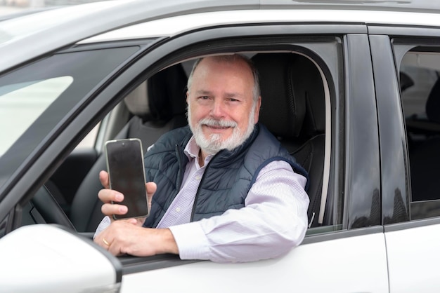 Portret van een oudere chauffeur in een auto of taxi met mobiele telefoon