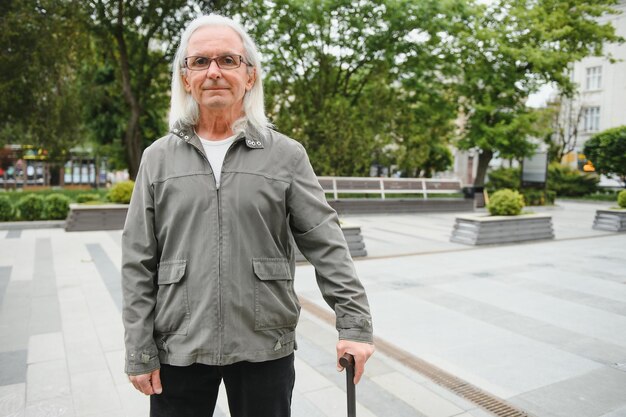 Portret van een oudere man die een wandelstok vasthoudt terwijl hij in het park rust