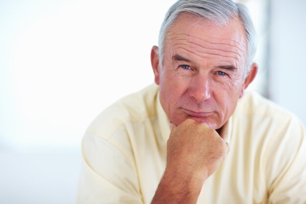 Portret van een oudere man en glimlach voor ontspanning in het weekend en met pensioen op de bank in huis met goede gezondheid oudere persoon gezicht en trots voor troost vrede en breek op de sofa in de lounge met een positieve stemming