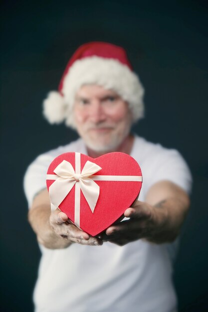 Foto portret van een oudere man met een kerstmuts in de sportschool met een cadeau in zijn handen kerstconcept