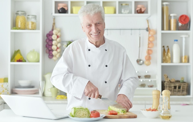 Portret van een oudere mannelijke chef-kok die salade kookt