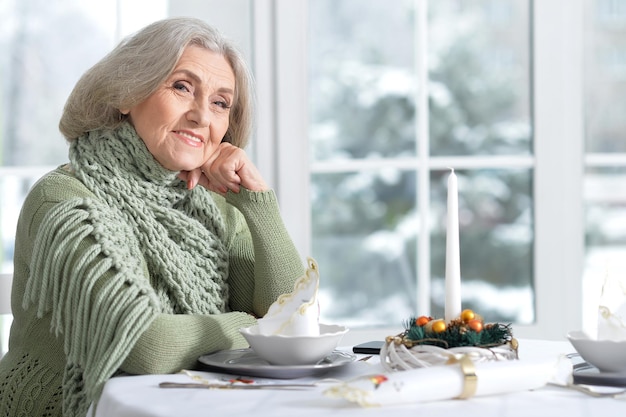 Portret van een oudere vrouw die aan tafel zit