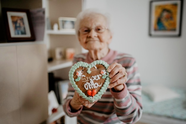Portret van een oudere vrouw die thuis een peperkoekje vasthoudt