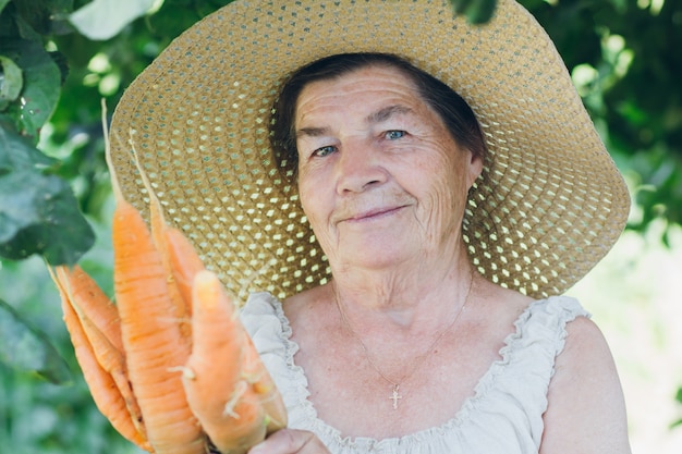 Portret van een oudere vrouw in een hoed met een wortel