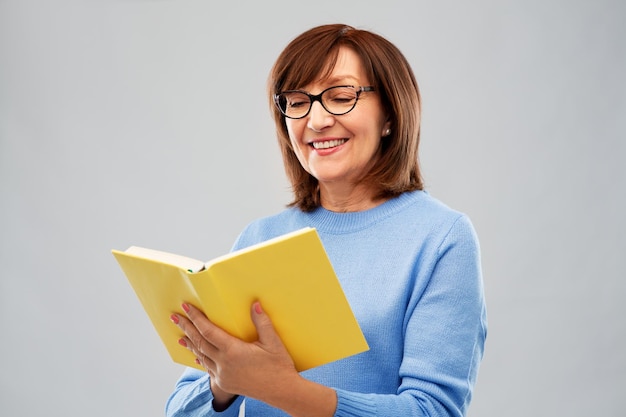 portret van een oudere vrouw met een bril die een boek leest