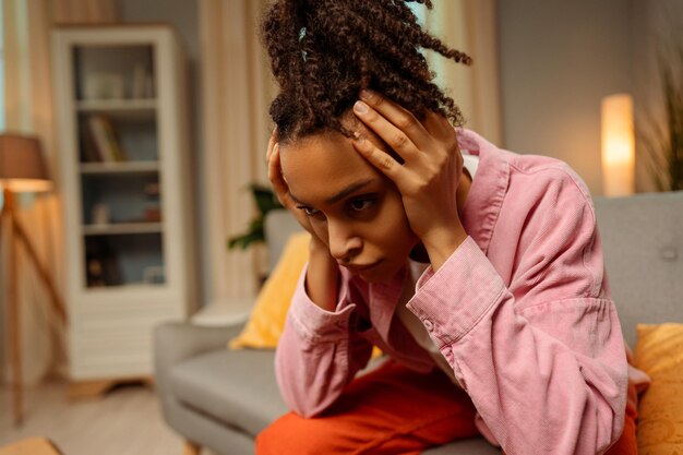 Foto portret van een overstuur afro-amerikaanse vrouw met hoofdpijn die slecht nieuws heeft ontvangen terwijl ze thuis in een kamer zit