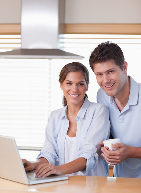 Portret van een paar dat laptop met behulp van terwijl het hebben van koffie