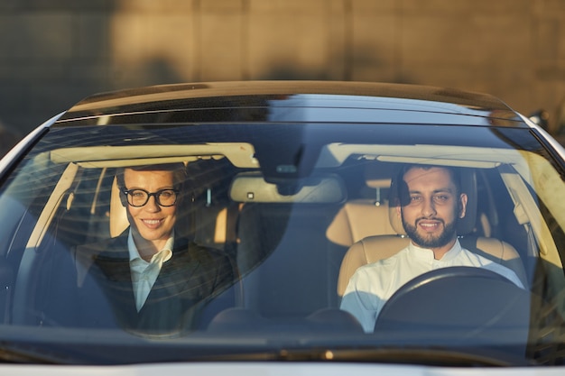 Portret van een paar glimlachen naar de camera tijdens het zitten in de auto en het rijden