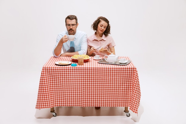 Portret van een paar man en vrouw die aan tafel zitten met een smakelijk ontbijt dat op wit wordt geïsoleerd