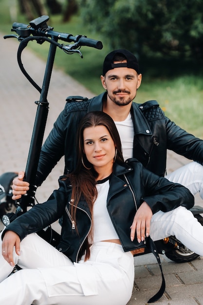 Portret van een paar zitten in de buurt van elektrische scooters, genieten van tijd in de natuur samen, twee geliefden op elektrische scooters. Mensen op scooters.