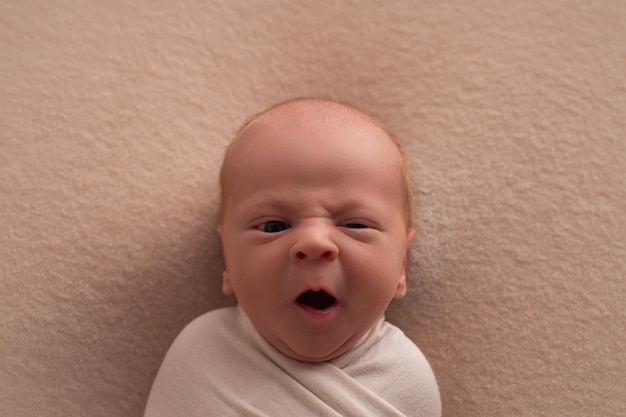 Portret van een pasgeboren baby op een beige achtergrond die geeuwt