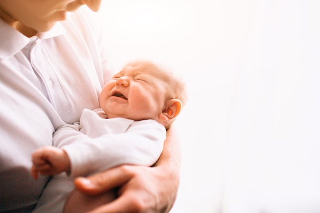 Portret van een pasgeboren baby. Vader houdt een kind in haar armen. Het eerste levensjaar. Zorg en gezondheid.