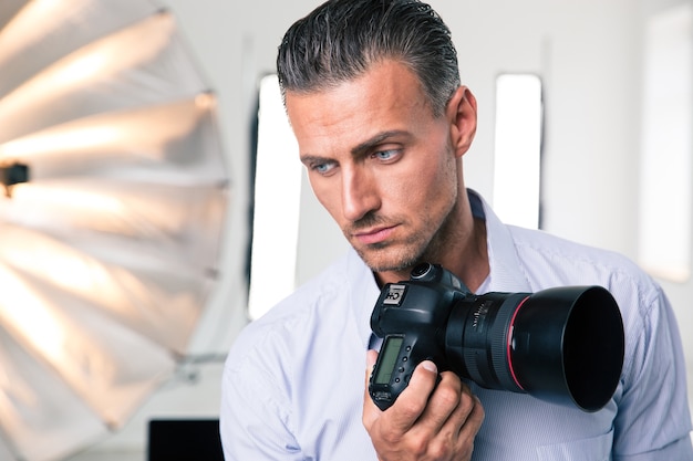 Portret van een peinzende fotograaf die camera in studio houdt