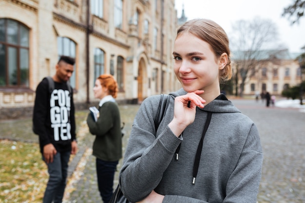 Portret van een peinzende jonge vrouw die buiten op de campus staat