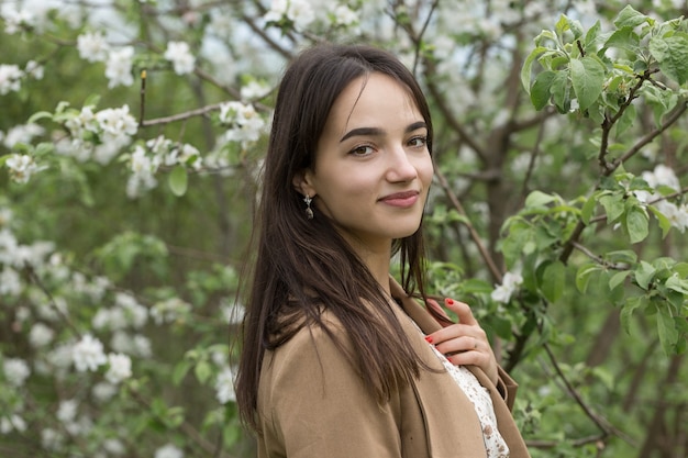 Portret van een positief vrolijk brunette meisje in een groen lentepark.