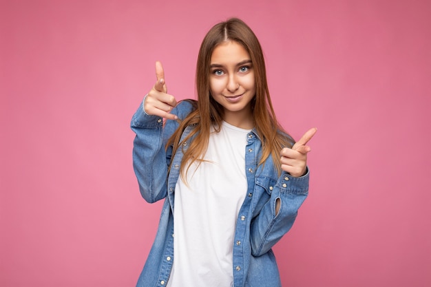 Portret van een positieve, gelukkige jonge, mooie donkerblonde vrouw met oprechte emoties die blauwe denim draagt