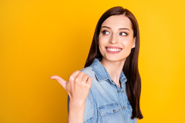 Portret van een positieve vrolijke meisjespromotor geeft aan dat de duimvinger van het verkooppunt copyspace is