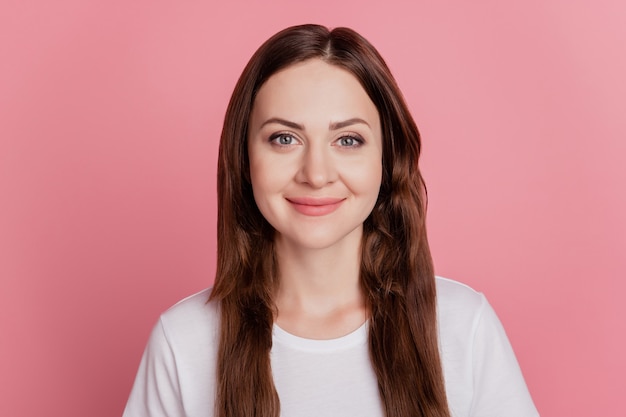 Portret van een positieve, vrolijke, schattige, mooie meid kijkt cameraglimlach op roze achtergrond