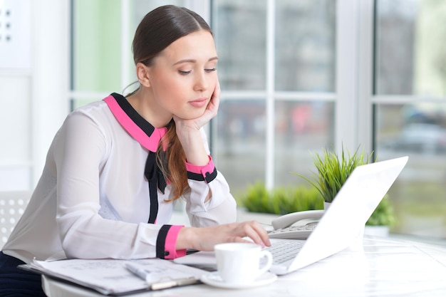 Portret van een prettige zakenvrouw met een laptop op kantoor