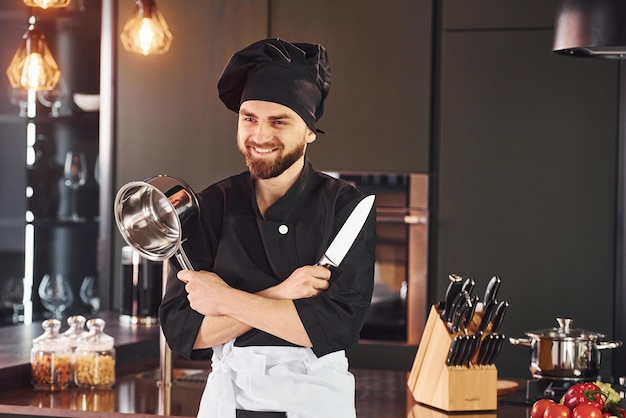 Portret van een professionele jonge chef-kok in uniform die poseert voor de camera in de keuken