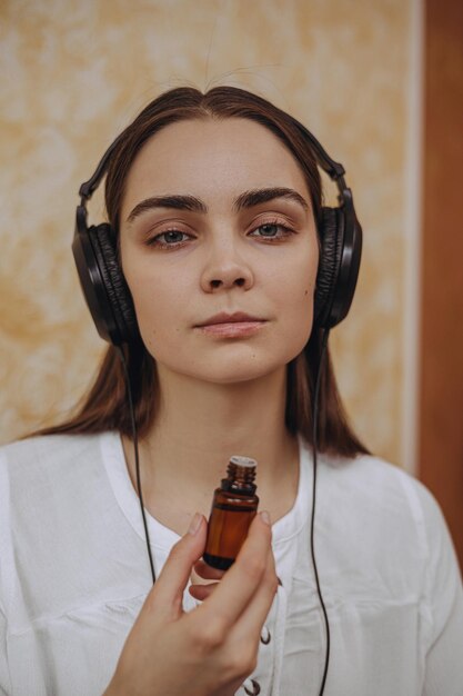 Portret van een rustige vrouw in een koptelefoon die naar muziek luistert en de geur van etherische olie ruikt