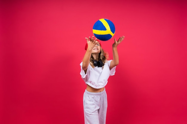 Portret van een schattig acht jaar oud meisje in volleybal outfit geïsoleerd op rode gele achtergrond