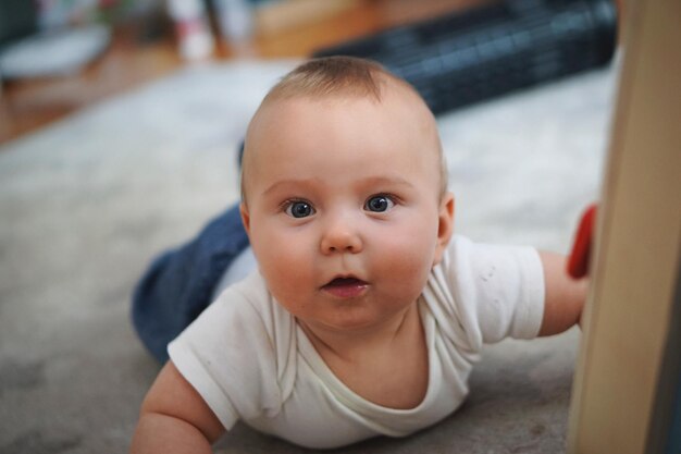 Foto portret van een schattig baby meisje dat thuis op het tapijt ligt