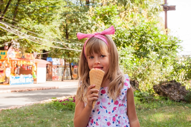 Portret van een schattig blond meisje met ijs op een wandeling in het park.