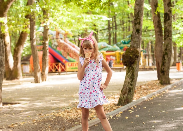 Portret van een schattig blond meisje met ijs op een wandeling in het park.