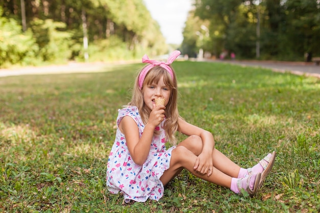 Portret van een schattig blond meisje met ijs op een wandeling in het park.