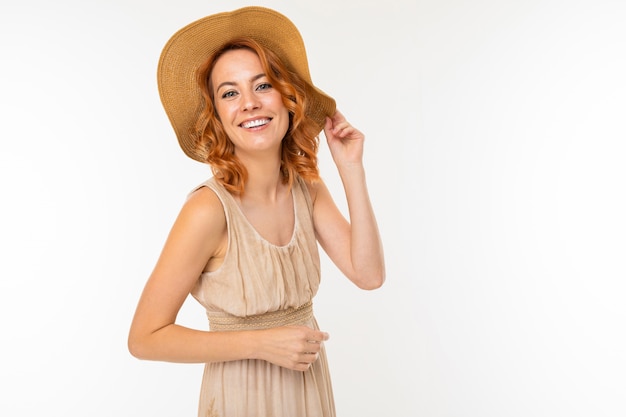 Portret van een schattig gelukkig charmant mooi blond meisje in een jurk en een zomer hoed op een witte muur met lege ruimte