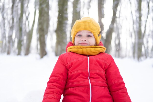 portret van een schattig, gelukkig lachend kindmeisje in een roze sneeuwpak dat in het winterbos loopt