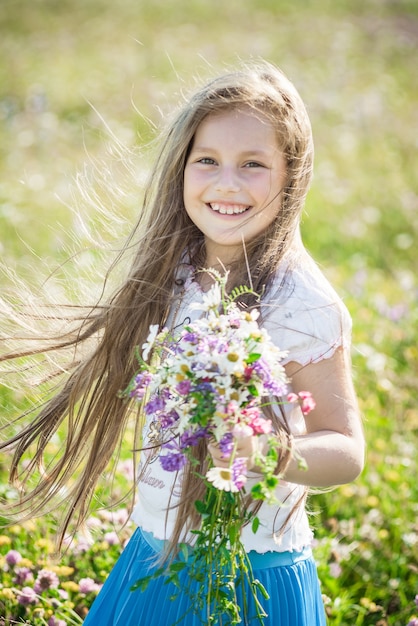 Portret van een schattig klein gelukkig zevenjarig meisje met lupine bloemen in een veld in de natuur buiten.