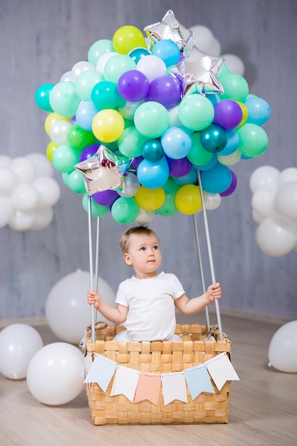 Portret van een schattig klein meisje dat in een mand met kleurrijke luchtballon zit