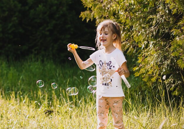 Portret van een schattig klein meisje dat zeepbellen blaast in het park in de zomer