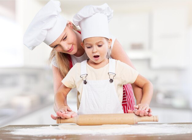 Portret van een schattig klein meisje en haar moeder die samen aan het bakken zijn
