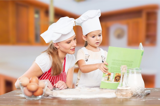 Portret van een schattig klein meisje en haar moeder die samen aan het bakken zijn