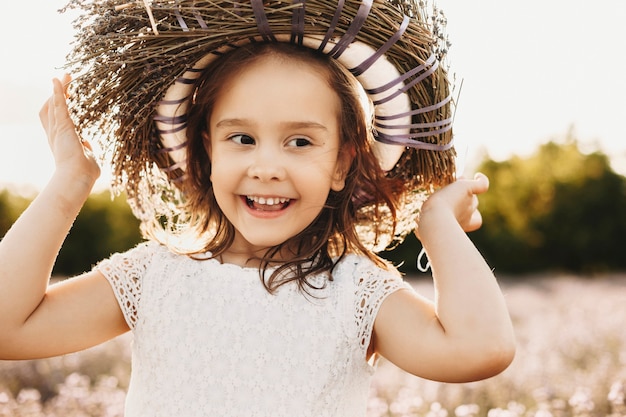 Portret van een schattig klein meisje glimlachend buiten close-up. Mooie jongen met een krans van bloemen wegkijken lachend tegen zonsondergang.