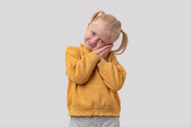 Portret van een schattig klein meisje in een gele sweatshirt geïsoleerd op witte achtergrond