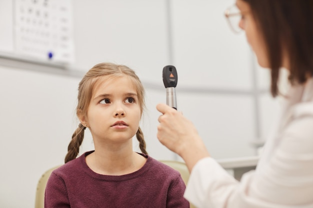 Portret van een schattig klein meisje kijken naar vrouwelijke optometrist tijdens visie test close-up