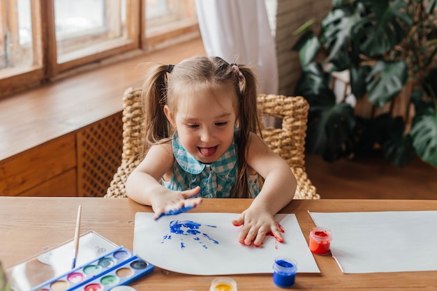 Portret van een schattig klein meisje tekent met verf en handen Geschilderde handpalmen voor kinderen