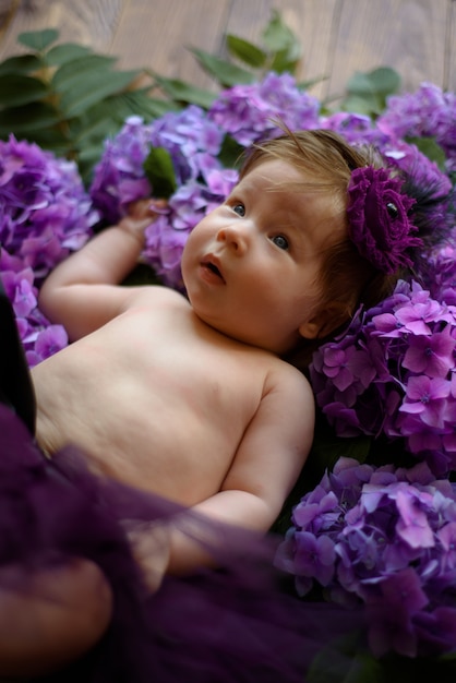 Portret van een schattig klein meisje (zes maanden oud). Baby ligt in de kleuren van paarse hortensia