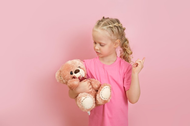 Portret van een schattig klein voorschools blond meisje dat een teddybeer vasthoudt